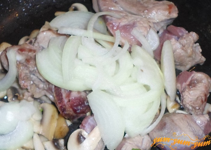 Добавить лук к мясу и грибам и обжарить несколько минут 